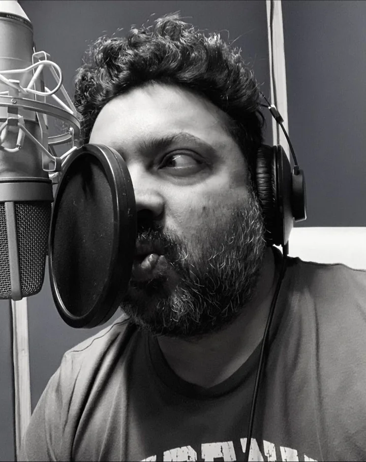 Abhinandan wearing headphones at a studio microphone, photographed in black and white.